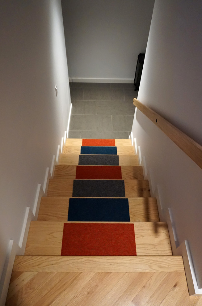 На фото: угловая лестница среднего размера в современном стиле с ступенями с ковровым покрытием и ковровыми подступенками с