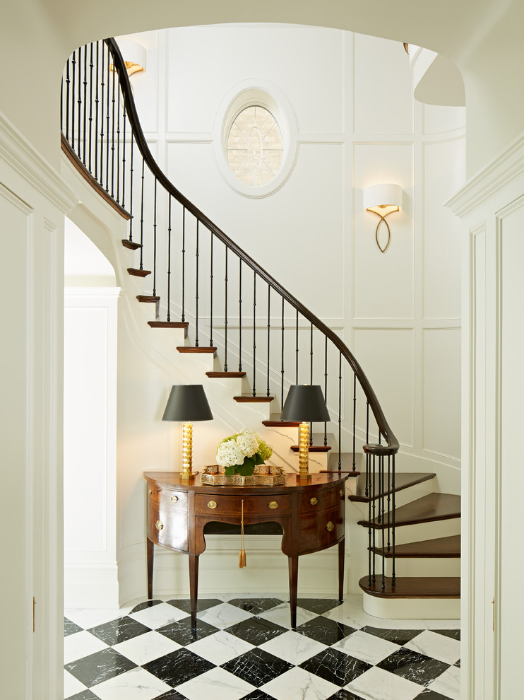 Идея дизайна: изогнутая лестница в классическом стиле с деревянными ступенями, крашенными деревянными подступенками и металлическими перилами