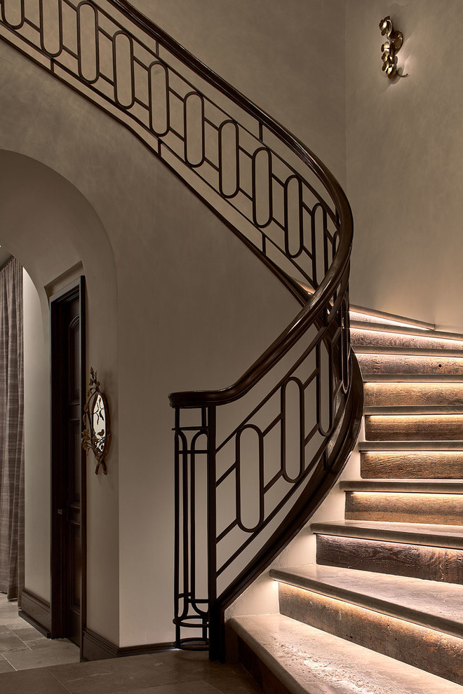 Идея дизайна: большая изогнутая лестница в стиле неоклассика (современная классика) с ступенями из известняка, подступенками из известняка и металлическими перилами