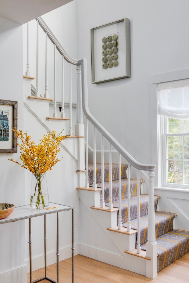 Small coastal carpeted l-shaped wood railing staircase in Boston with painted wood risers.