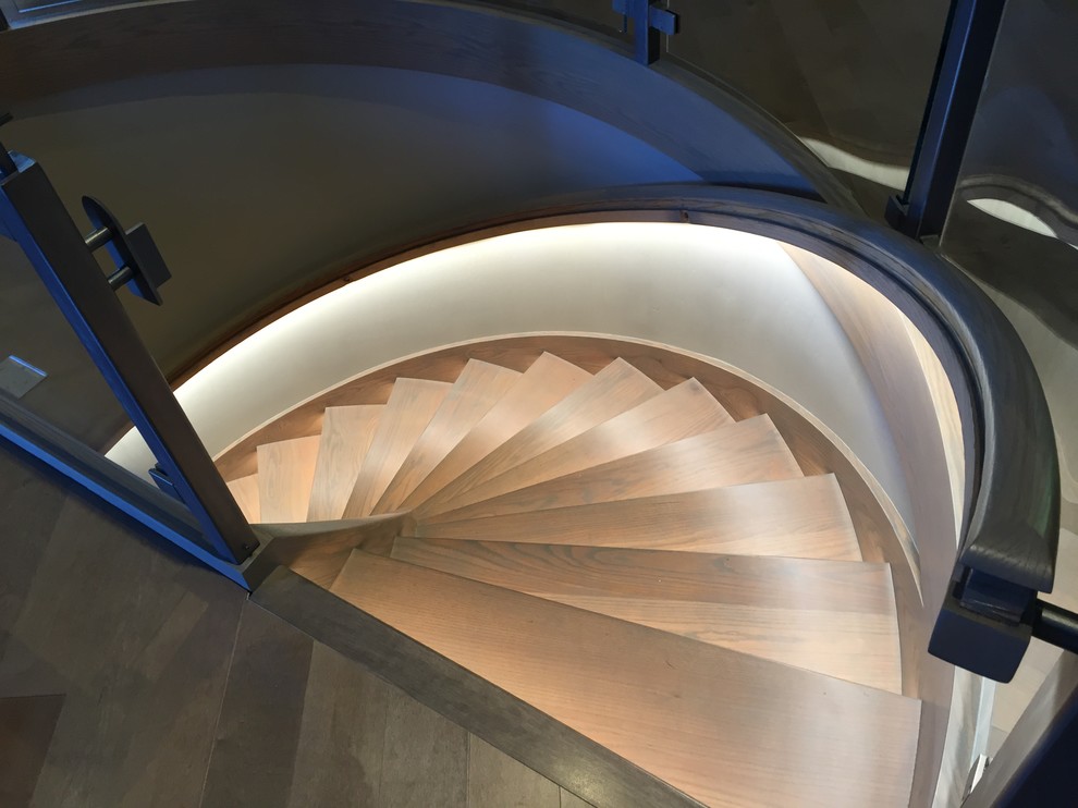Идея дизайна: большая винтовая лестница в современном стиле с деревянными ступенями и деревянными перилами