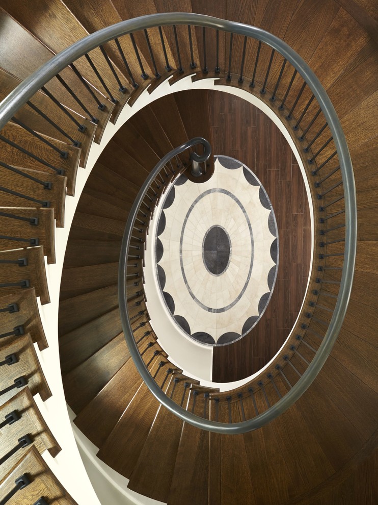 Cette image montre un grand escalier peint courbe traditionnel avec des marches en bois.