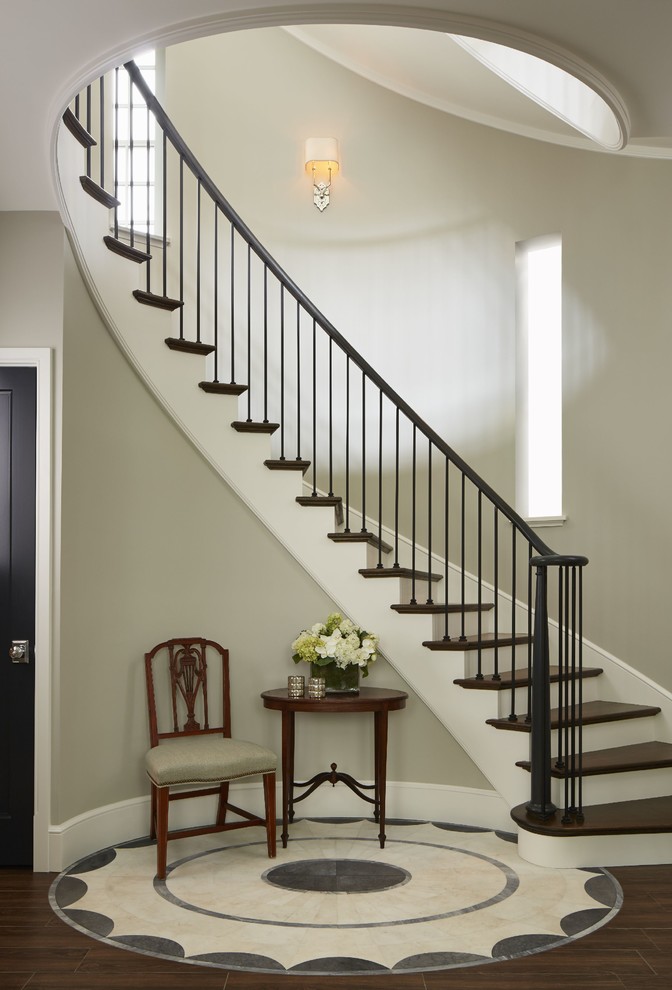 Large elegant wooden curved staircase photo in Chicago with painted risers