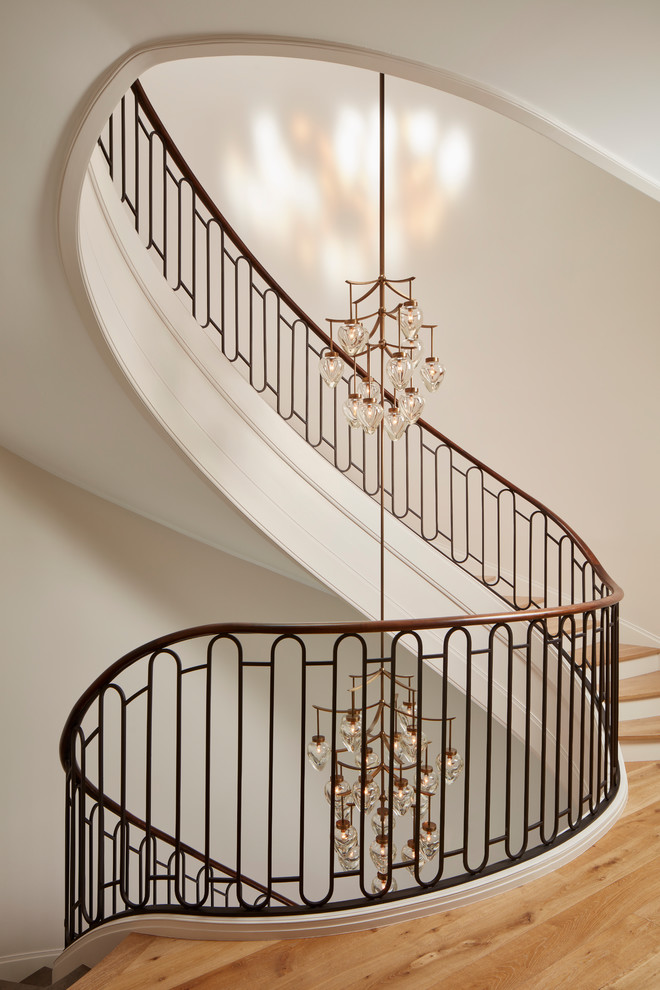 Staircase - huge traditional wooden curved metal railing staircase idea in Chicago with painted risers