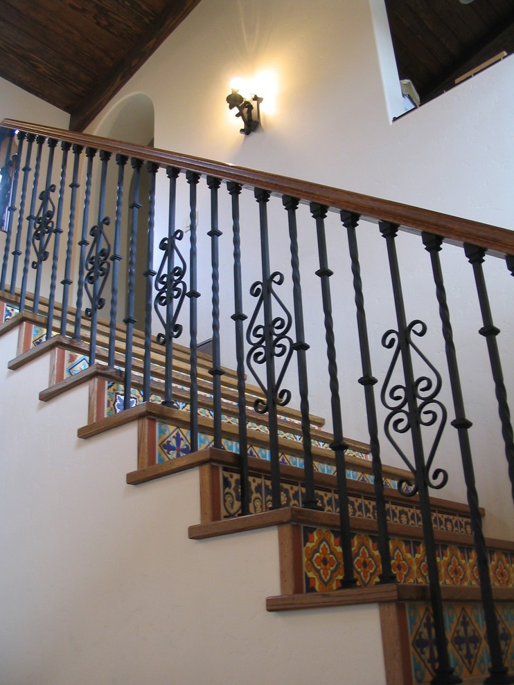Cette image montre un grand escalier droit méditerranéen avec des marches en bois, des contremarches carrelées et un garde-corps en métal.