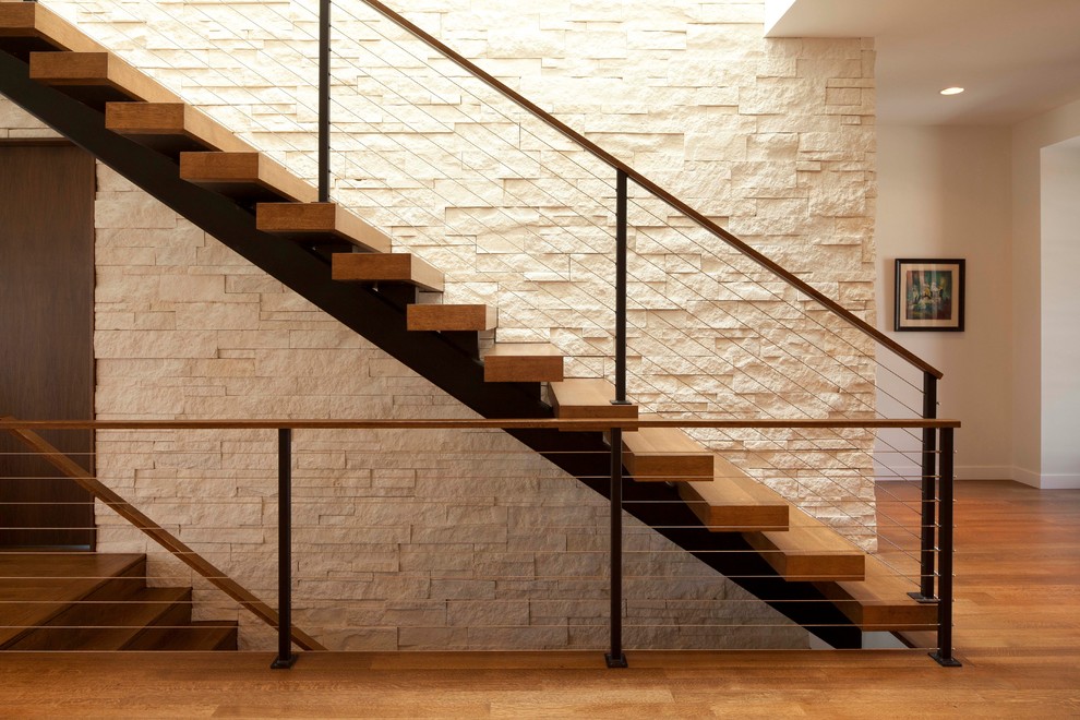 Idée de décoration pour un escalier droit minimaliste avec un garde-corps en câble et des marches en bois.