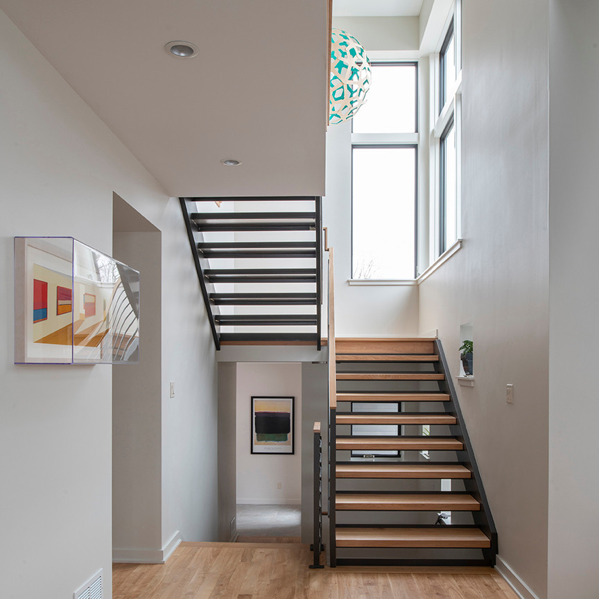 Imagen de escalera en U actual de tamaño medio con escalones de madera, contrahuellas de metal y barandilla de varios materiales