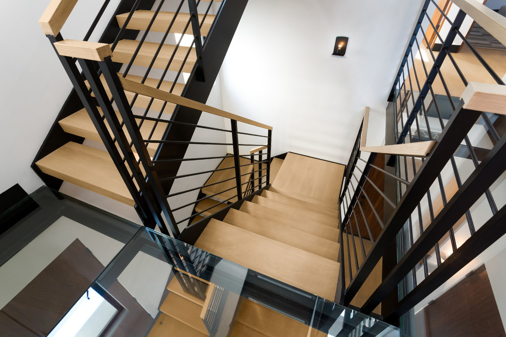 Idée de décoration pour un grand escalier sans contremarche design en U avec des marches en bois et un garde-corps en métal.