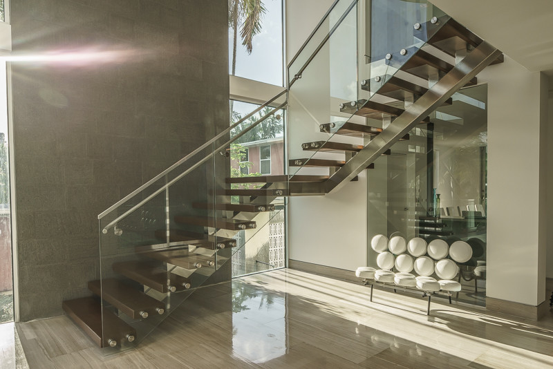 Ejemplo de escalera suspendida moderna grande sin contrahuella con escalones de madera y barandilla de vidrio