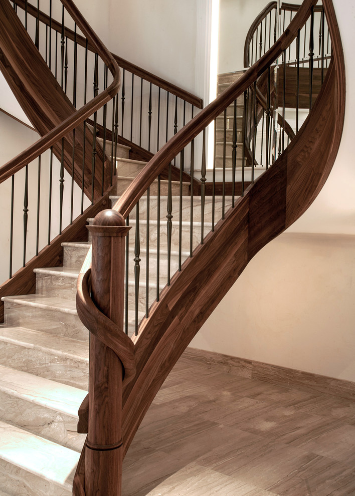 Modelo de escalera curva tradicional grande con escalones de mármol, contrahuellas de madera y barandilla de varios materiales