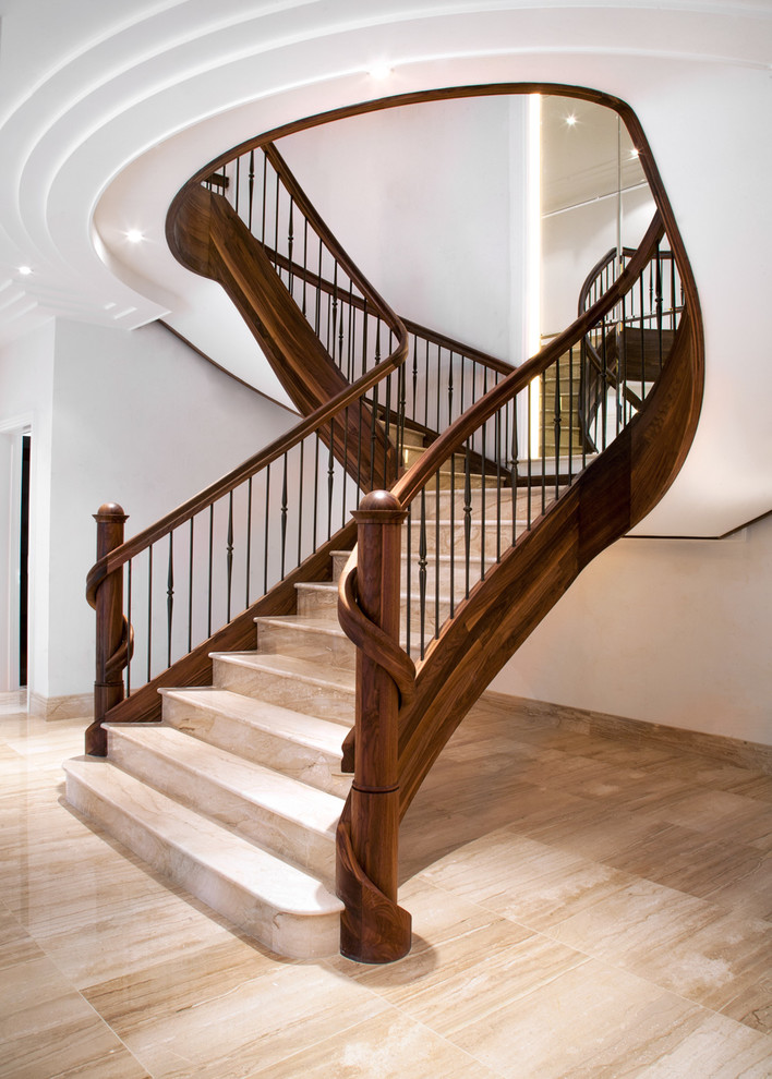 На фото: большая изогнутая деревянная лестница в классическом стиле с мраморными ступенями и перилами из смешанных материалов с