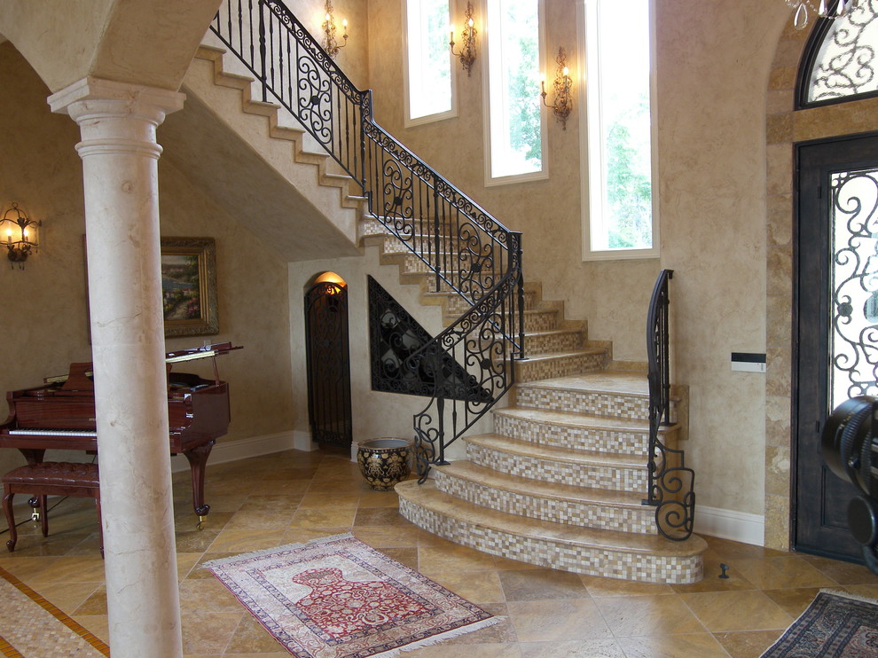Источник вдохновения для домашнего уюта: огромная изогнутая лестница в классическом стиле с ступенями из травертина, подступенками из плитки и металлическими перилами