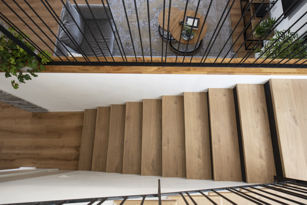Modelo de escalera en U clásica renovada de tamaño medio con escalones de madera, contrahuellas de madera y barandilla de metal