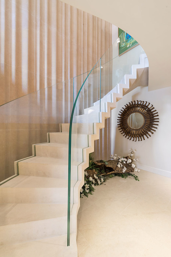 Inspiration for a large transitional limestone curved glass railing staircase remodel in Other with limestone risers