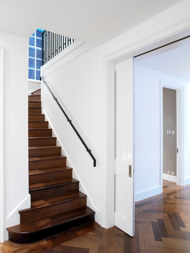 Example of a mid-sized transitional wooden l-shaped metal railing staircase design in New York with wooden risers