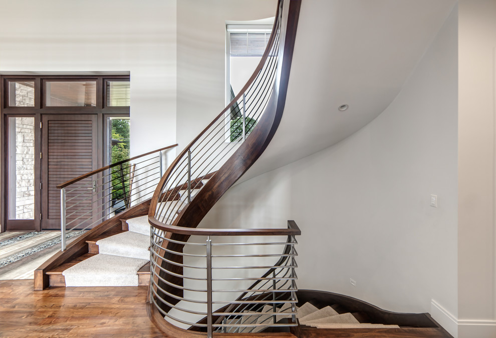 Diseño de escalera curva actual grande con escalones de madera, contrahuellas de madera y barandilla de varios materiales