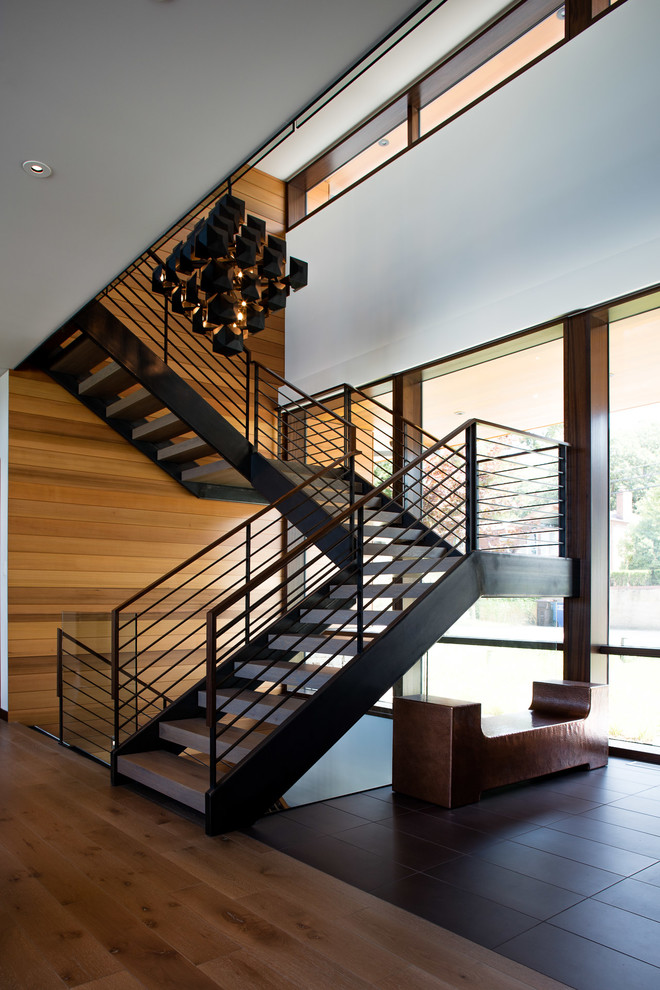 Cette image montre un escalier sans contremarche design en U avec des marches en bois et un garde-corps en métal.