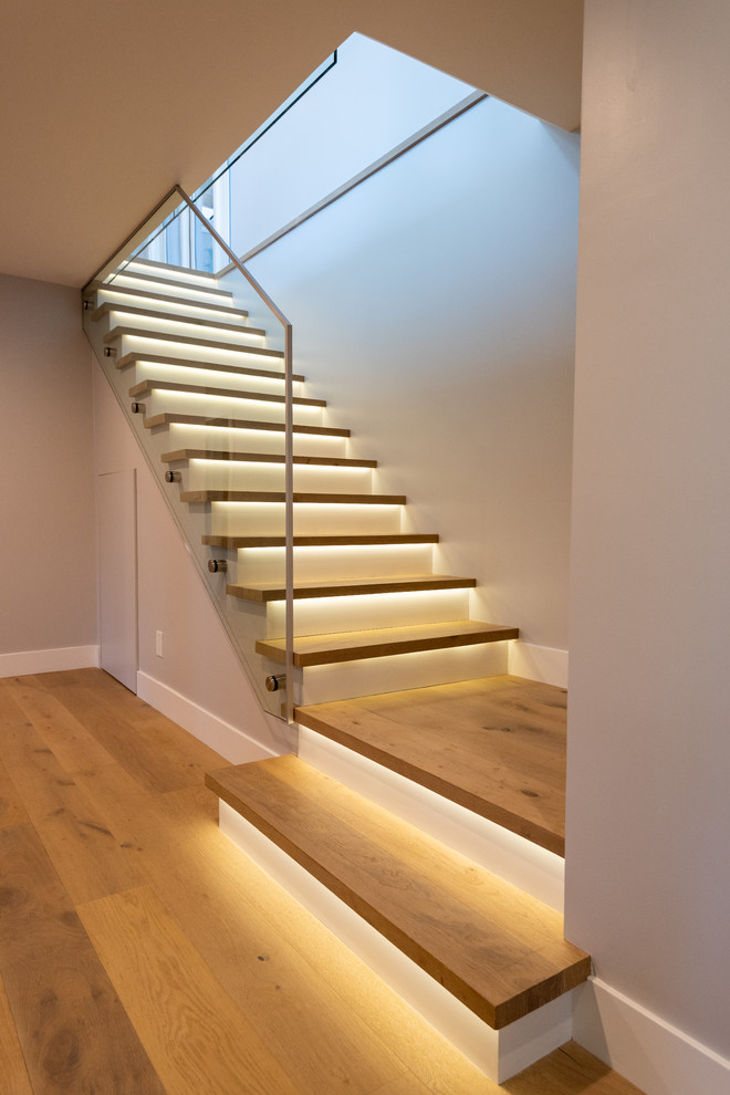 Cette photo montre un escalier droit moderne de taille moyenne avec des marches en bois, des contremarches en bois et un garde-corps en verre.
