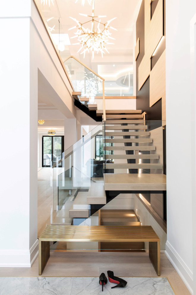 На фото: огромная п-образная лестница в современном стиле с стеклянными перилами и ступенями из плитки без подступенок