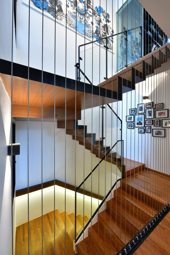 На фото: п-образная деревянная лестница в современном стиле с деревянными ступенями и перилами из тросов