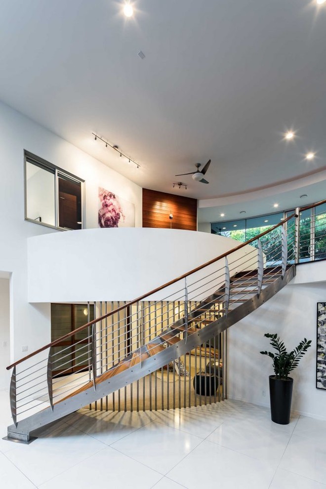 This is an example of a large contemporary wood curved wire cable railing staircase in San Francisco with metal risers.