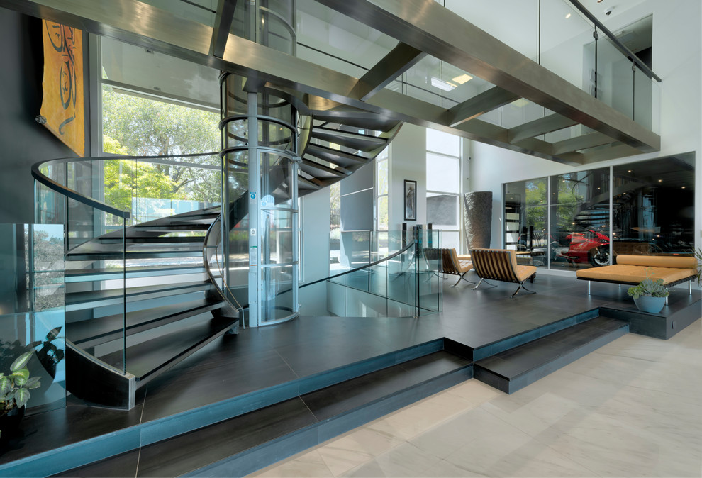 На фото: огромная винтовая лестница в современном стиле с стеклянными перилами без подступенок с