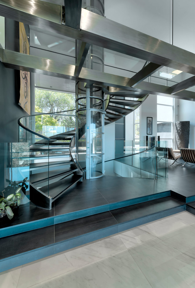 На фото: огромная винтовая лестница в современном стиле с стеклянными перилами без подступенок