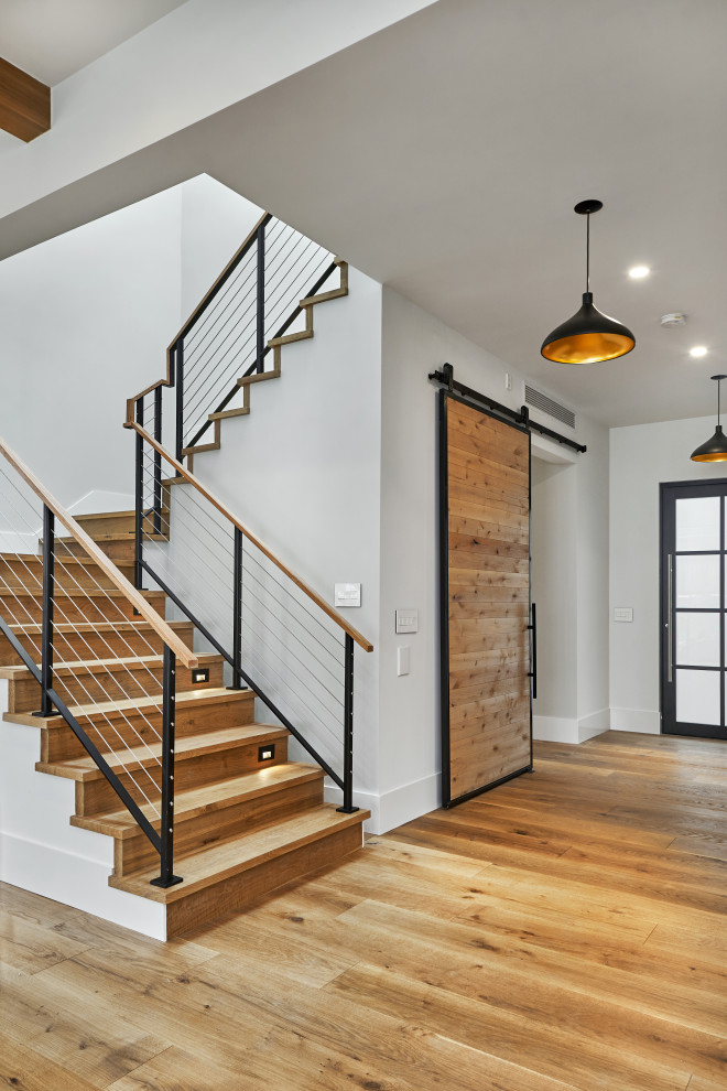 Cette image montre un escalier minimaliste en L de taille moyenne avec des marches en bois, des contremarches en bois et un garde-corps en câble.