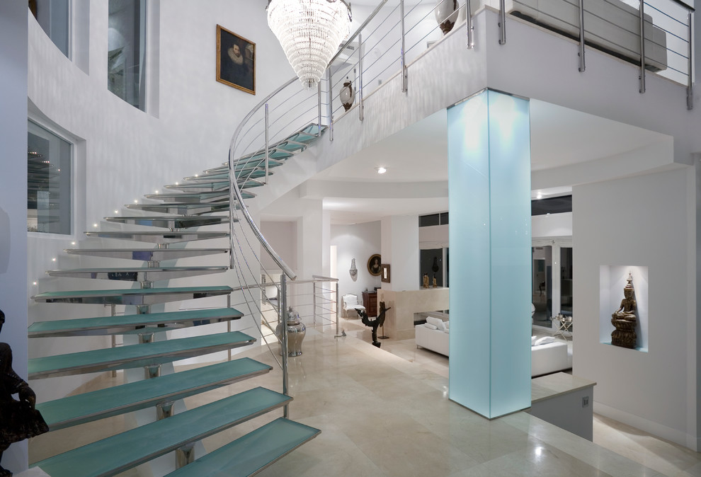 На фото: большая изогнутая лестница в современном стиле с стеклянными ступенями без подступенок