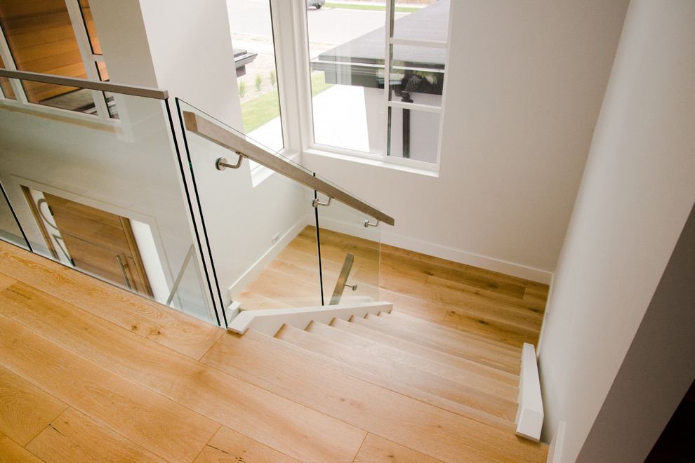 Ejemplo de escalera suspendida minimalista de tamaño medio sin contrahuella con escalones de madera y barandilla de vidrio