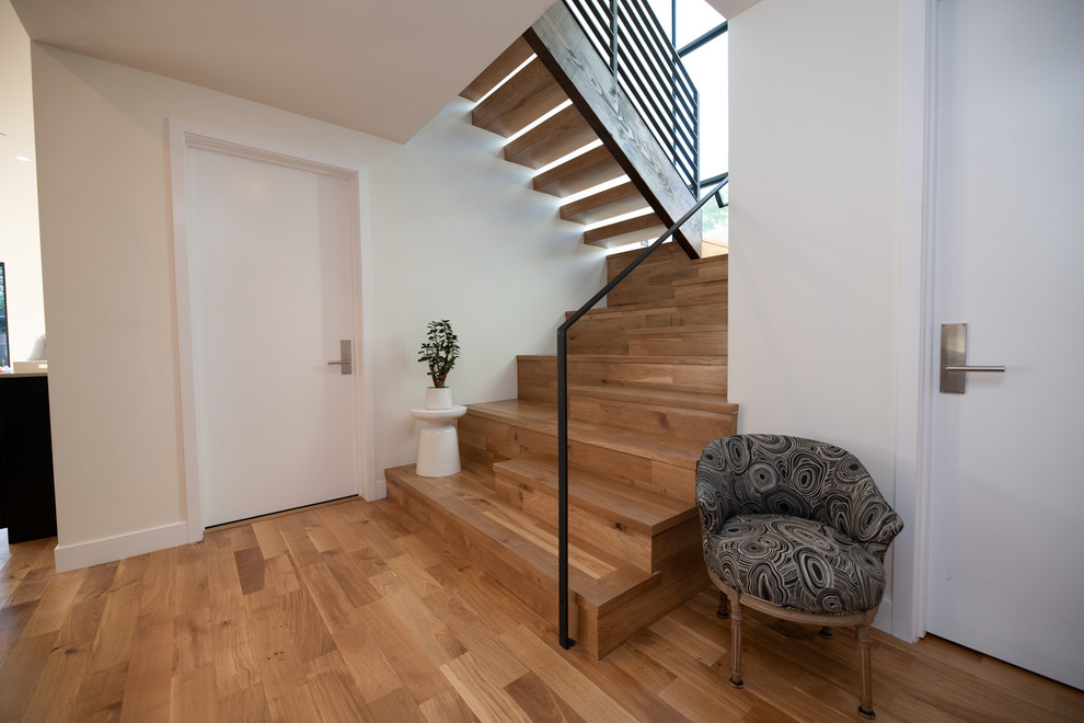 Aménagement d'un escalier flottant rétro de taille moyenne avec des marches en bois, des contremarches en bois et un garde-corps en métal.
