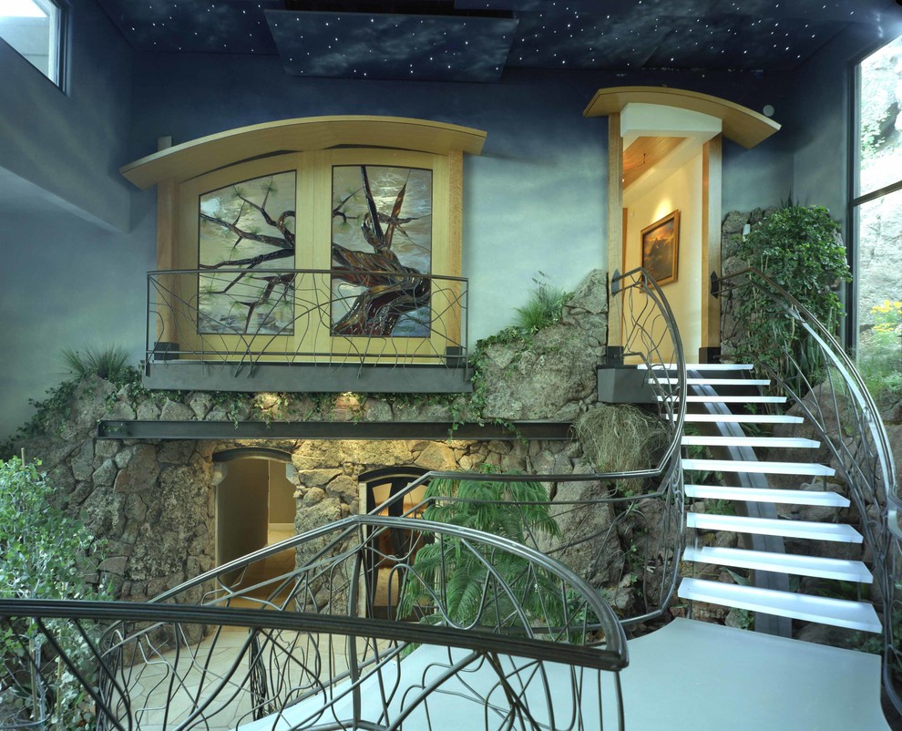 Стильный дизайн: большая винтовая металлическая лестница в современном стиле с стеклянными ступенями - последний тренд