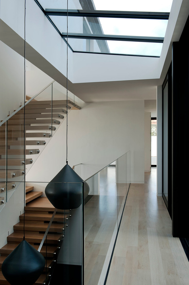 Diseño de escalera suspendida contemporánea sin contrahuella con barandilla de vidrio