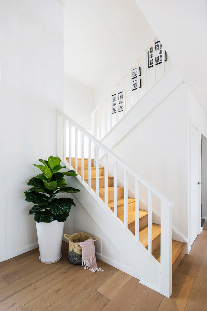 Cette photo montre un grand escalier tendance en L avec des marches en bois, des contremarches en bois et un garde-corps en bois.