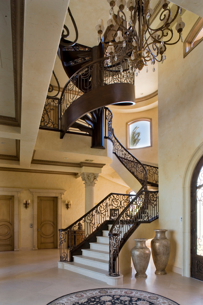 На фото: огромная изогнутая лестница в классическом стиле с металлическими перилами