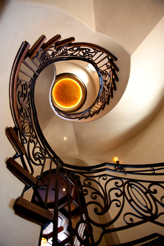 Стильный дизайн: огромная винтовая деревянная лестница в средиземноморском стиле с деревянными ступенями - последний тренд