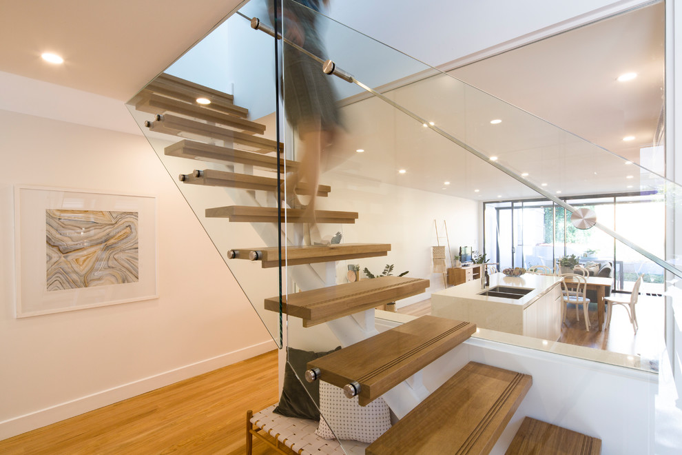 Aménagement d'un escalier droit contemporain de taille moyenne avec des marches en bois, des contremarches en métal et un garde-corps en verre.