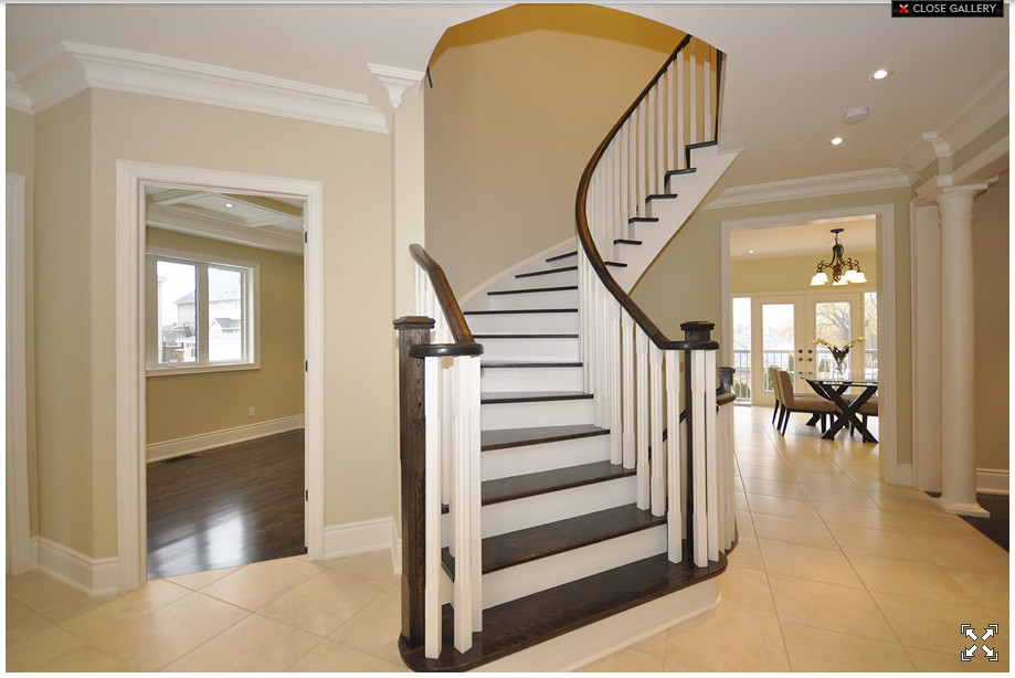 На фото: изогнутая лестница среднего размера в современном стиле с деревянными ступенями и крашенными деревянными подступенками с
