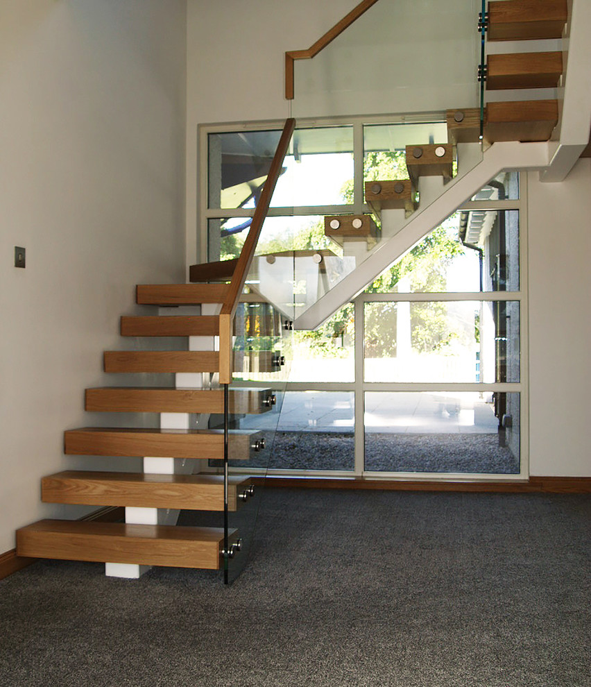 Immagine di una scala sospesa minimalista di medie dimensioni con pedata in legno, nessuna alzata e parapetto in vetro