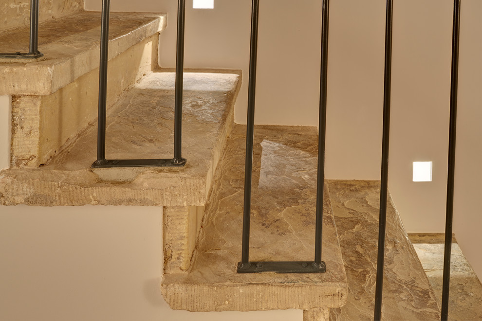Diseño de escalera recta tradicional grande con escalones de piedra caliza, contrahuellas de piedra caliza y barandilla de metal