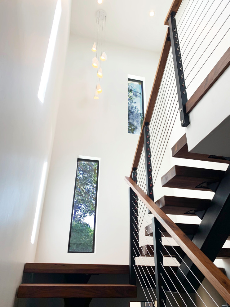 На фото: п-образная лестница в стиле модернизм с деревянными ступенями и перилами из тросов