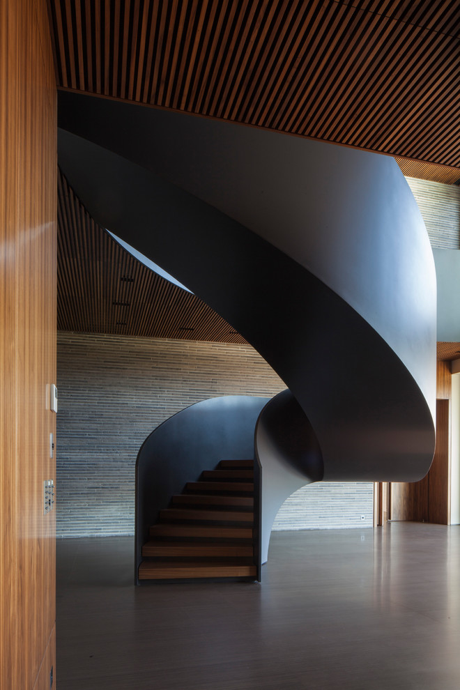 Idée de décoration pour un très grand escalier hélicoïdal minimaliste avec des marches en bois et des contremarches en béton.