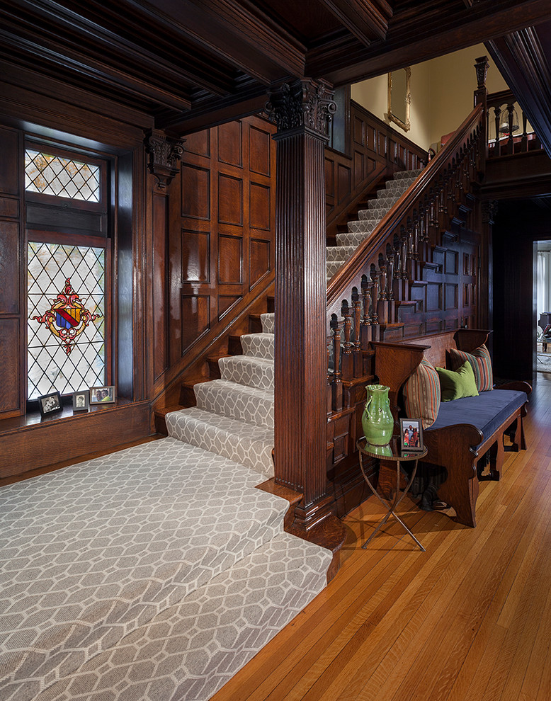 Large victorian carpeted u-shaped wood railing staircase in New York with wood risers.