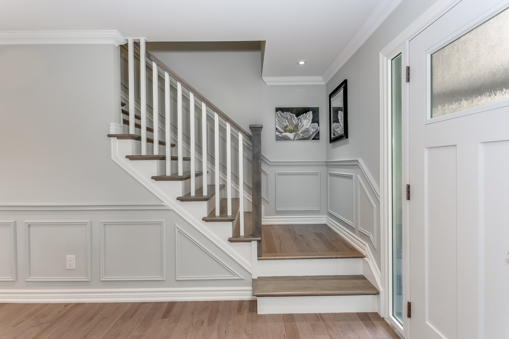 Imagen de escalera en L clásica de tamaño medio con escalones de madera, contrahuellas de madera pintada y barandilla de madera