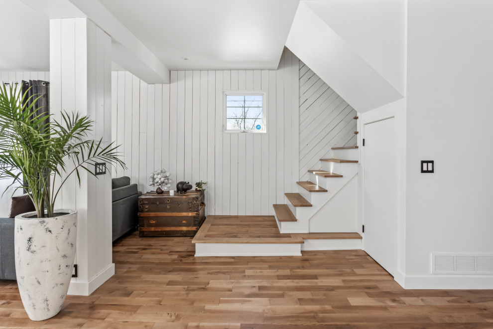 Großes, Repräsentatives, Offenes Landhaus Wohnzimmer mit Holzdielenwänden, weißer Wandfarbe und braunem Holzboden in Montreal