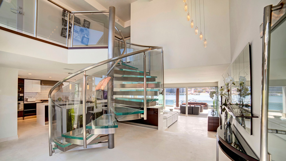 Idée de décoration pour un grand escalier hélicoïdal design avec des marches en verre, des contremarches en métal et éclairage.