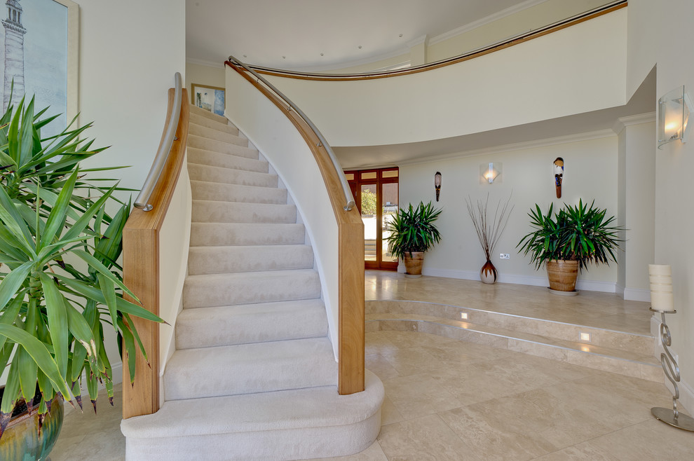 Large contemporary carpeted curved staircase in Devon with carpeted risers.