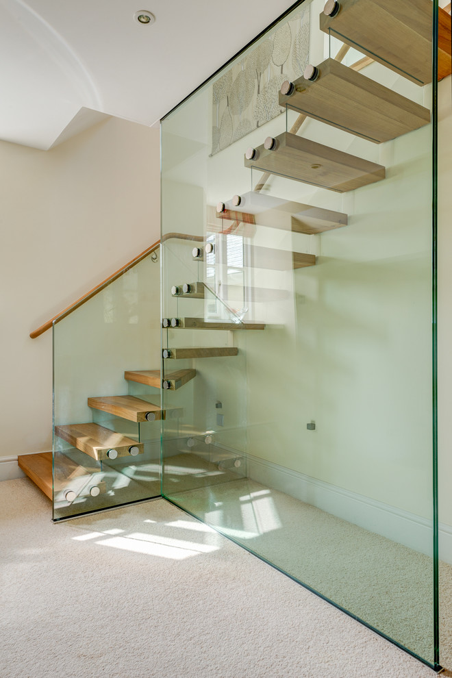 Idée de décoration pour un escalier en L de taille moyenne avec des marches en bois et des contremarches en verre.