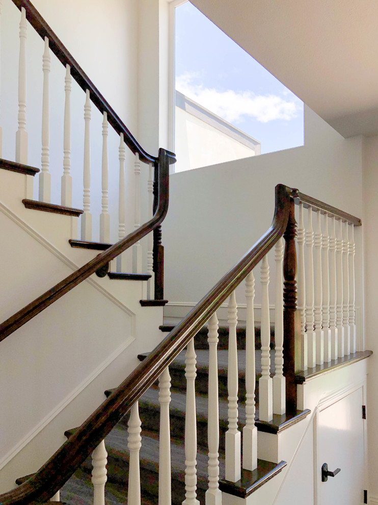 Foto de escalera en U clásica de tamaño medio con contrahuellas de madera, barandilla de madera y escalones enmoquetados