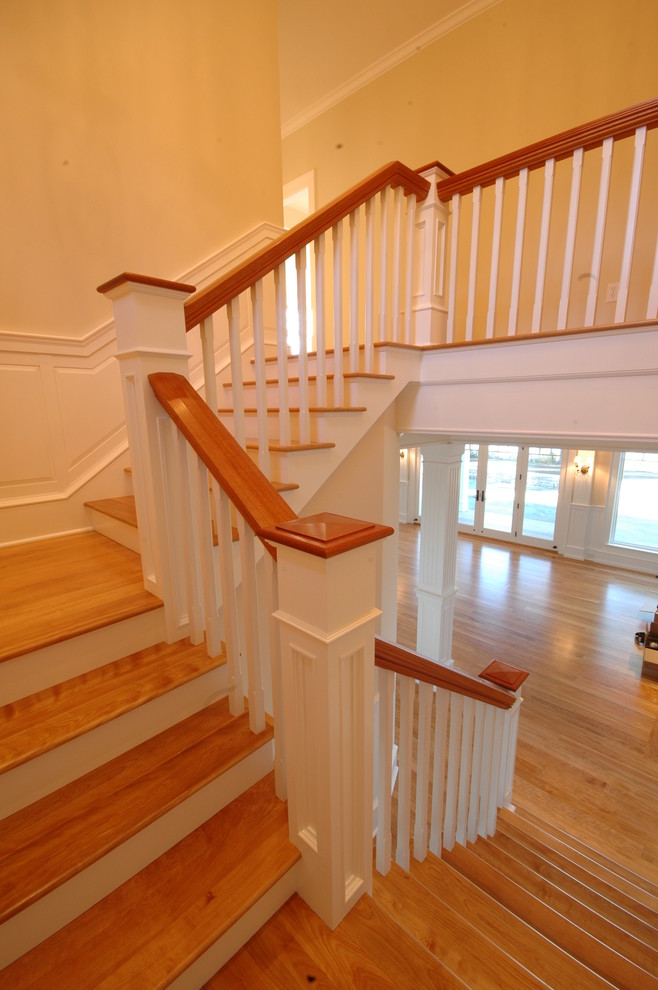 Ejemplo de escalera recta clásica grande con escalones de madera, contrahuellas de madera pintada y barandilla de madera